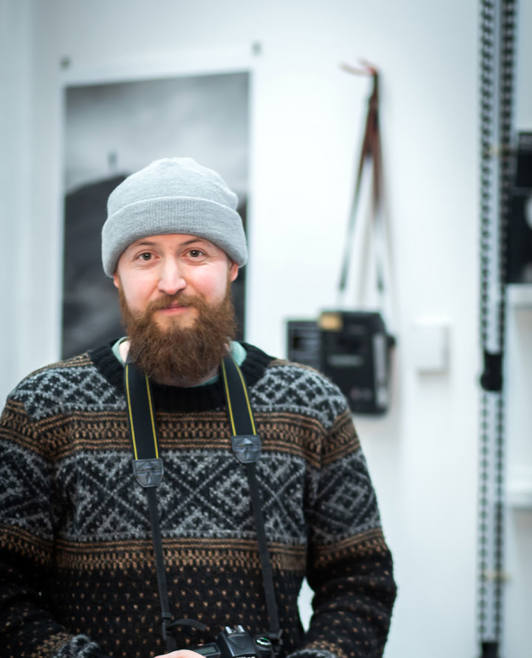 Bearded student holding a Nikon DSLR camera and smiling in a photography studio. Bearded student holding a Nikon DSLR camera and smiling in a photography studio.